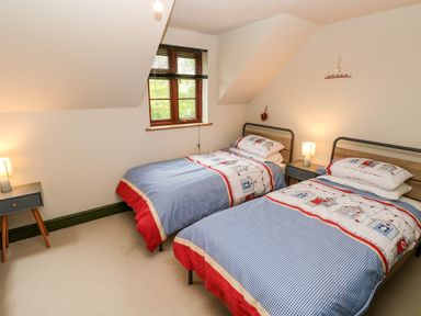 A bedroom with two single beds and two bedside tables with lamps at Bwthyn Canol in Haverfordwest