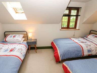 A bedroom with three single beds with patterned bedding a nightstand and a lamp at Bwthyn Canol in Haverfordwest