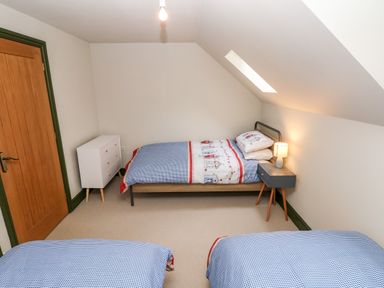 A bedroom with two single beds a white chest of drawers and a bedside table with a lamp at Bwthyn Canol in Haverfordwest