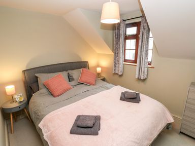 A bedroom with a double bed two side tables with lamps a window with curtains and a chest of drawers at Bwthyn Canol in Haverfordwest