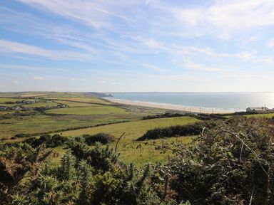 A coastal landscape with green fields and a beach by the sea at Bwthyn Canol in Haverfordwest
