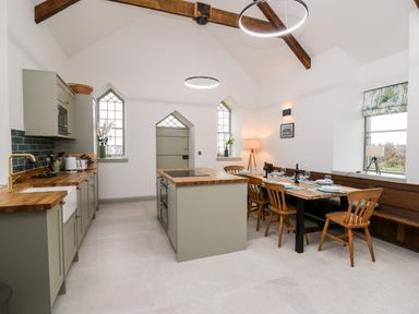 A kitchen with wooden countertops dining table with chairs and built in bench at Ysgoldy Brynwyre in Llanrhystud