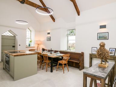 A kitchen dining area with wooden chairs a bench and an island at Ysgoldy Brynwyre in Llanrhystud