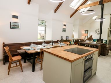A kitchen and dining area with wooden chairs and table set for dining in an open living space at Ysgoldy Brynwyre in Llanrhystud