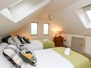 A bedroom with two beds pillows and bedside lamp at Ysgoldy Brynwyre in Llanrhystud
