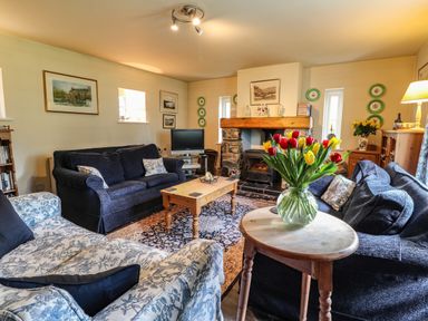 A living room with sofas a wooden coffee table a fireplace and flowers on a small table at Tyddyn Bach in Newport Pembrokeshire