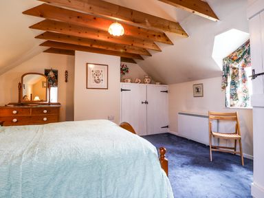 A bedroom with a wooden dresser and mirror white cupboard a wooden chair and a bed at Tyddyn Bach Newport Pembrokeshire