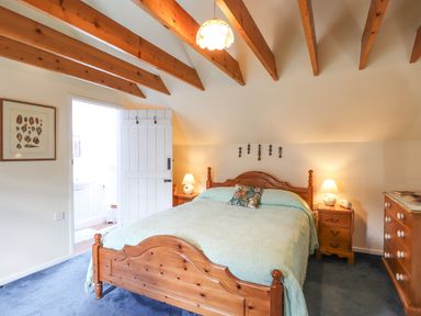 A bedroom with a wooden bed and bedside tables with lamps at Tyddyn Bach in Newport Pembrokeshire