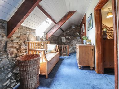 A hallway with a wooden bench a wicker basket and a wooden dresser with flowers on it at Tyddyn Bach in Newport Pembrokeshire