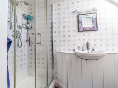 A bathroom with a glass shower enclosure and a white sink under a square mirror at Tyddyn Bach Newport Pembrokeshire