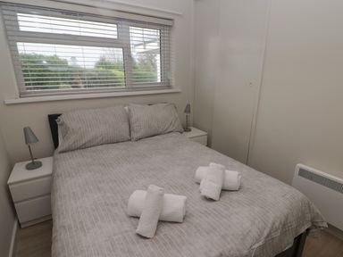 A bedroom with a double bed two bedside tables with lamps a window and towels on the bed at 21 Coedrath Park in Saundersfoot