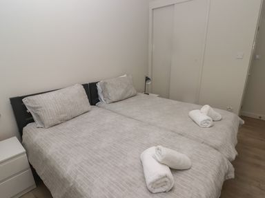 A bedroom with two single beds side by side with striped bedding and rolled towels at 21 Coedrath Park in Saundersfoot