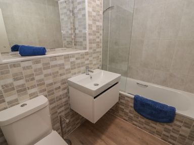 A bathroom with a toilet sink bathtub and blue towels at 21 Coedrath Park Saundersfoot