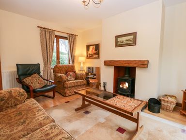A living room with armchairs a fireplace and a wooden coffee table at Friars Fold in Newby Bridge