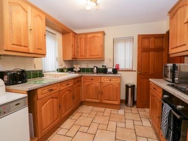 A kitchen with wooden cabinets tiled floor and appliances at Friars Fold in Newby Bridge