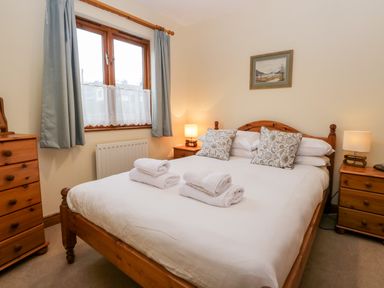 A bedroom with a wooden bed and bedside tables with lamps at Friars Fold in Newby Bridge