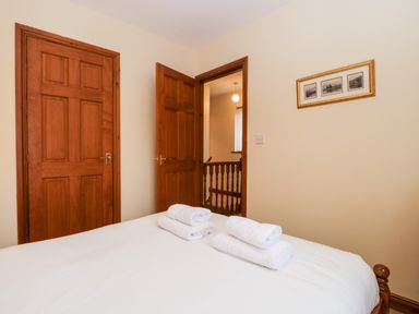 A bedroom with a bed with folded towels on it two wooden doors and a framed picture on the wall at Friars Fold in Newby Bridge