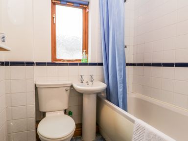 A bathroom with a toilet sink bathtub and blue shower curtain at Friars Fold in Newby Bridge