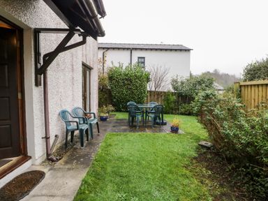 A garden with plastic chairs and a table on a patio at Friars Fold in Newby Bridge