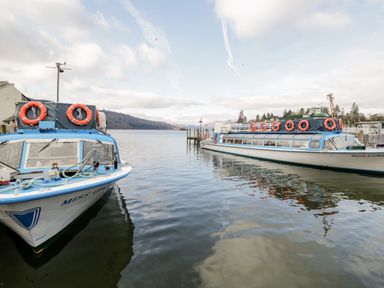 Two boats docked on a lake with life rings on them near a wooden pier at Friars Fold in Newby Bridge