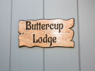 A wooden sign with the text Buttercup Lodge mounted on a gray wall at Buttercup Lodge in Misterton