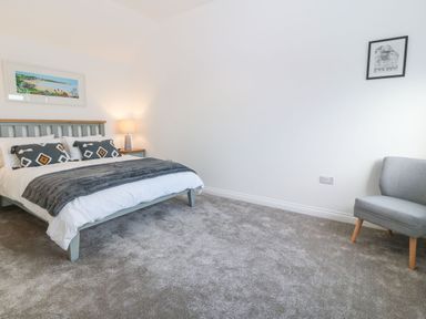 A bedroom with a bed pillows lamp and an armchair at Yr Hen Feudy in Moelfre