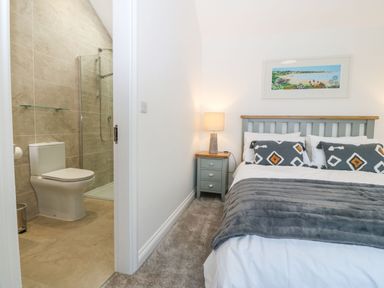 A bedroom with a bed a side table and lamp with an adjoining bathroom with a toilet and shower at Yr Hen Feudy in Moelfre