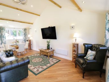 A living room with green leather armchairs a wooden coffee table a dining table with chairs and curtains at FAIRFIELD in Clee Hill
