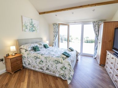 A bedroom with a double bed bedside tables a wardrobe and large glass doors at FAIRFIELD in Clee Hill