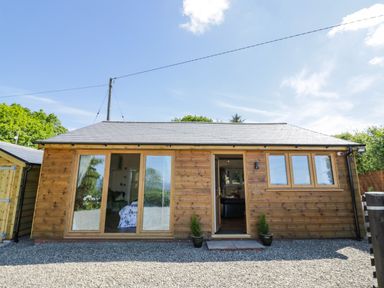 A wooden single-story house with glass doors and windows surrounded by gravel at FAIRFIELD in Clee Hill