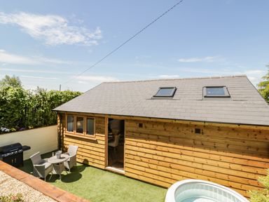 An outdoor area with wooden cabin table and chairs a grill and a small pool at FAIRFIELD in Clee Hill