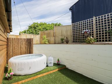 A small outdoor patio area with an inflatable hot tub and potted plants surrounded by wooden and concrete fencing at FAIRFIELD in Clee Hill