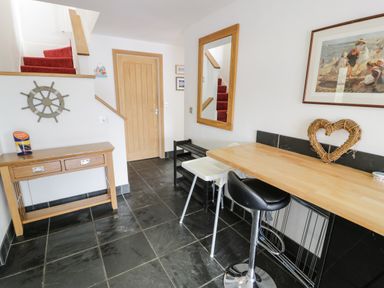 A hallway with a wooden table and a bar counter with two chairs at Bwthyn Awel in Church Bay near Cemaes Bay