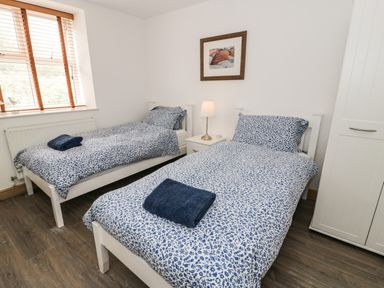 A bedroom with two single beds with blue patterned bedding and a nightstand with a lamp at Bwthyn Awel in Church Bay near Cemaes Bay