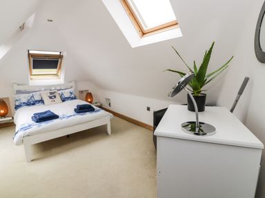 A bedroom with a bed a dresser a potted plant and two skylights at Bwthyn Awel in Church Bay near Cemaes Bay