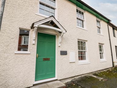 A white textured exterior wall with a green door and translucent windows at Bridgend Cottages in Howey near Llandrindod Wells