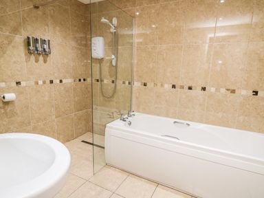 A bathroom with a bathtub a shower area and a sink at Bridgend Cottages in Howey near Llandrindod Wells