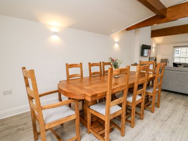 A dining room with a wooden table and chairs with a vase of flowers on the table at Bridgend Cottages in Howey near Llandrindod Wells