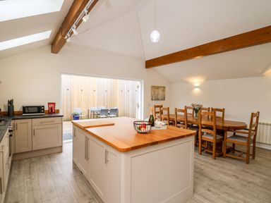 A kitchen and dining area with wooden dining table and chairs and a kitchen island with fruit basket at Bridgend Cottages Howey near Llandrindod Wells