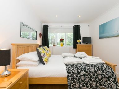A bedroom with a bed and floral pillows towels on bed and wooden furniture at The Waves in St Ives