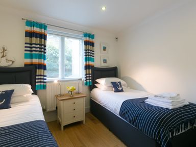 A bedroom with two single beds and a small nightstand in between at The Waves in St Ives