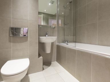 A bathroom with a toilet sink and bathtub with shower at The Waves in St Ives