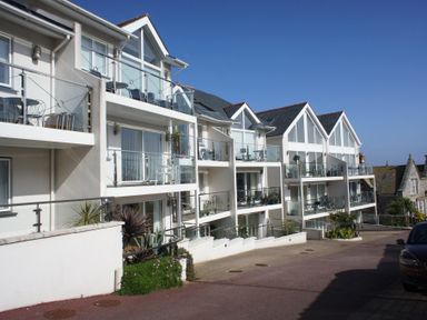 A modern apartment building with balconies and glass railings on a sunny day at The Waves in St Ives
