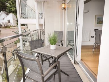 A balcony with a table and three chairs and a plant on the table at The Waves in St Ives