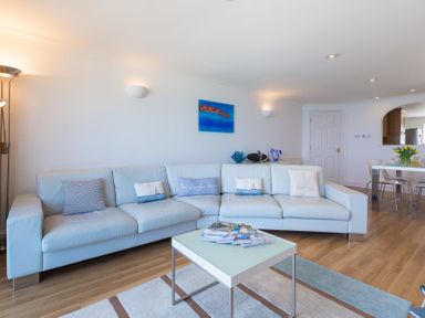 A living room with a light blue sofa and a coffee table with magazines at Turquarze in Carbis Bay