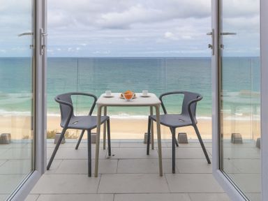 A balcony with two chairs and a table overlooking the ocean at Turquarze in Carbis Bay