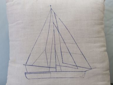 A cushion with a blue line drawing of a sailboat on fabric at Turquarze in Carbis Bay