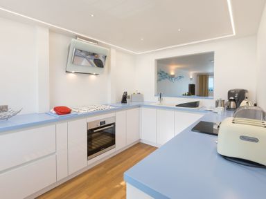 A kitchen with blue countertops white cabinets and wooden floor at Turquarze in Carbis Bay
