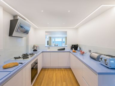 A kitchen with blue countertops a gas cooker and bread on a cutting board at Turquarze in Carbis Bay