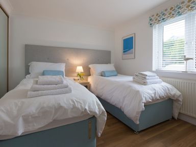 A bedroom with two single beds each with white bedding and towels on top at Turquarze in Carbis Bay
